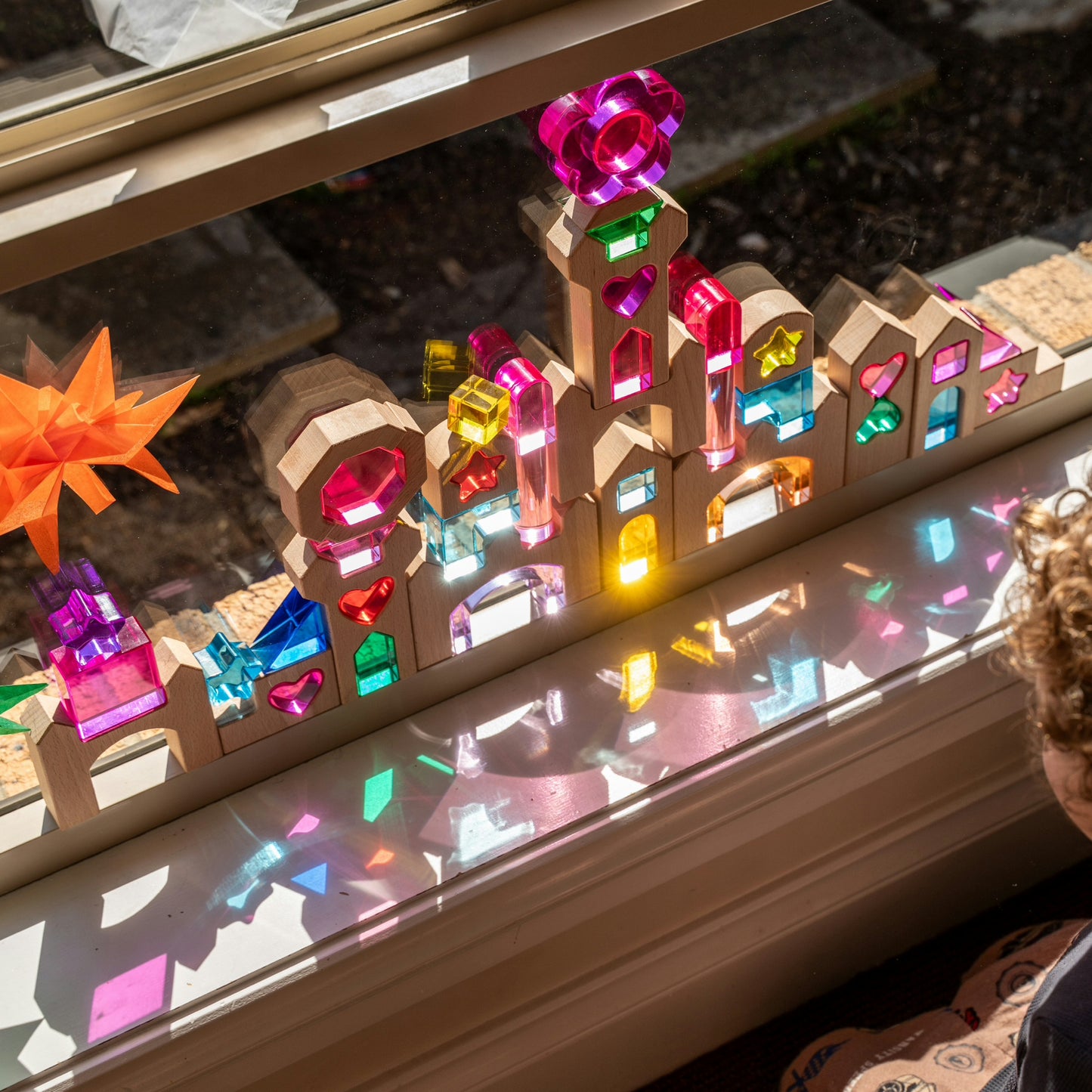 Star of the Lucite Kingdom set with lucite hearts, stars, octagon and arches paired with wooden castle blocks glowing on a window sill. 