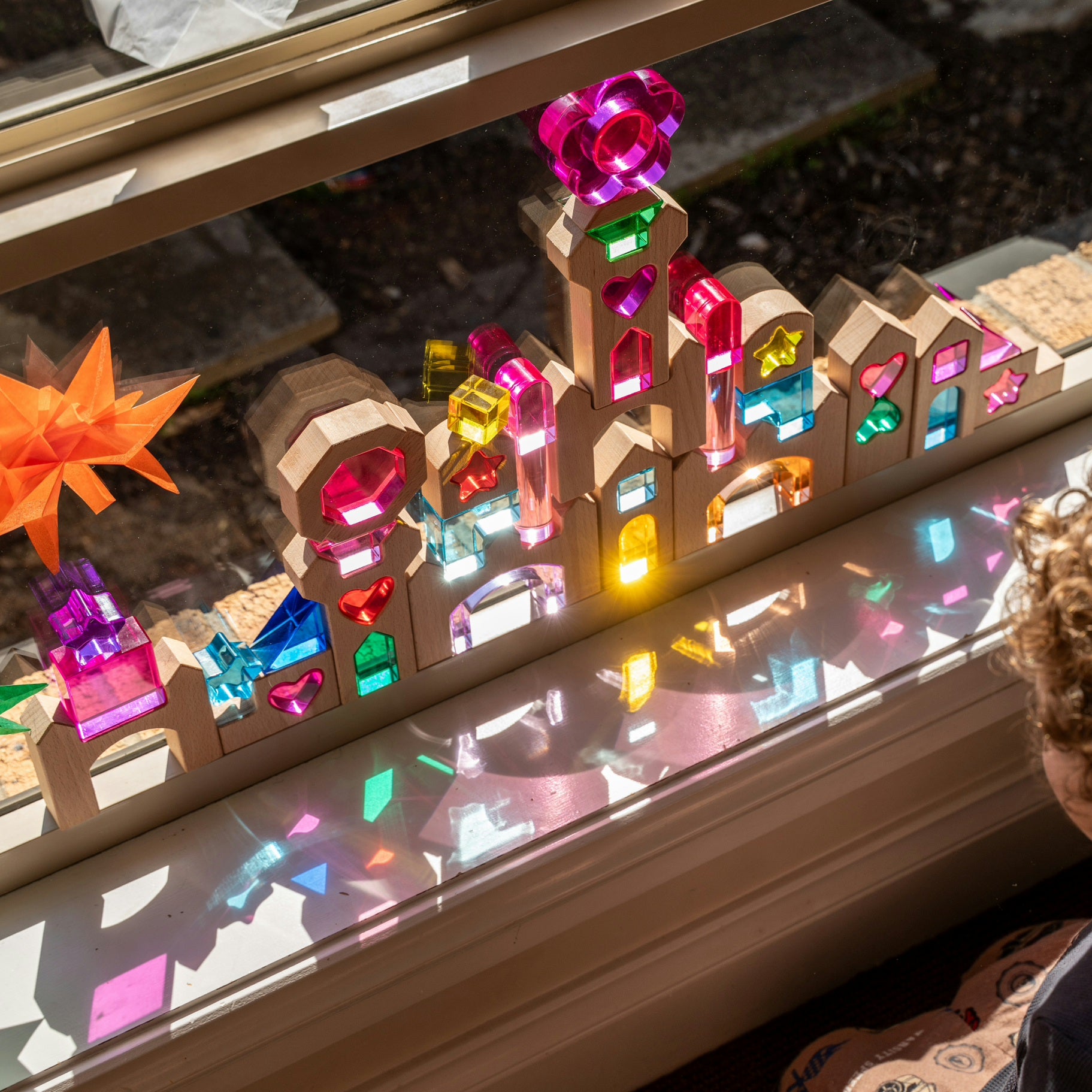 Star of the Lucite Kingdom set with lucite hearts, stars, octagon and arches paired with wooden castle blocks glowing on a window sill. 