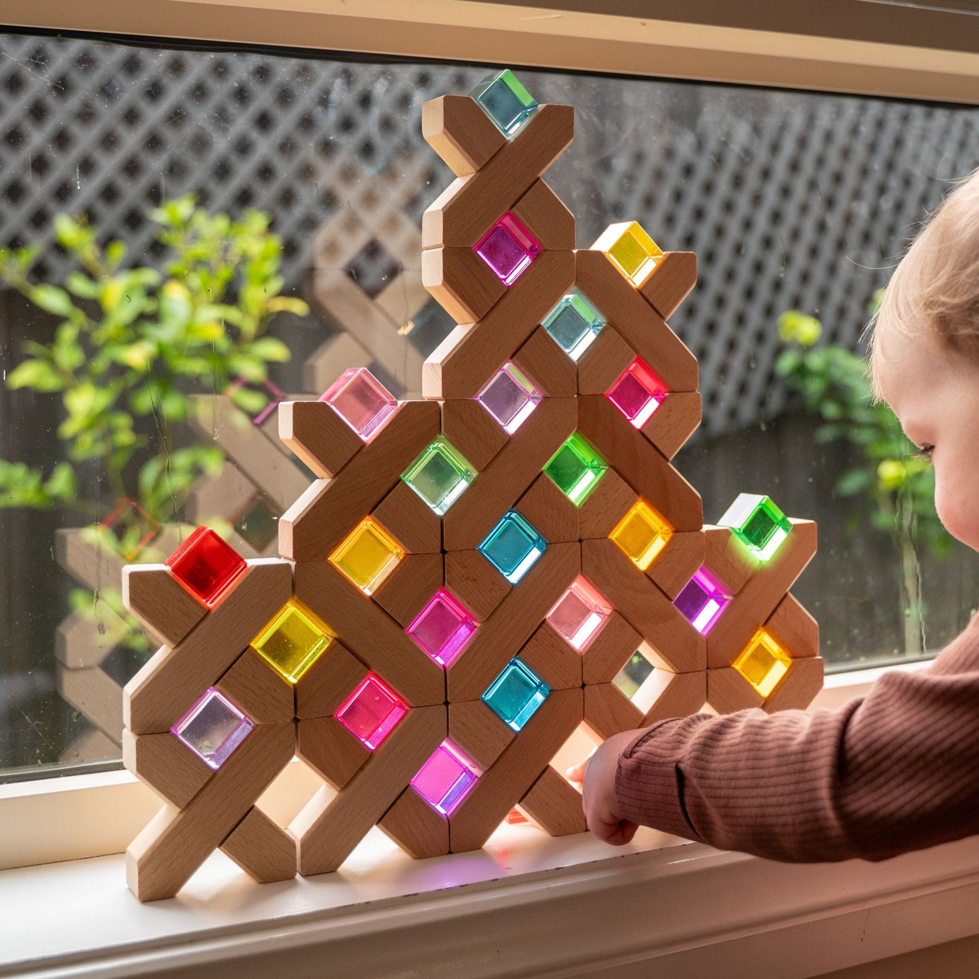 Rainbow lucite cubes balanced on X-shaped wooden blocks